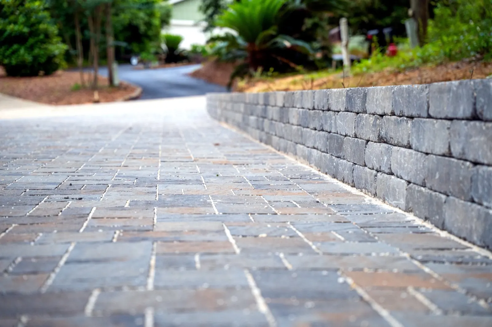 Paver driveway built alongside a block retaining wall on a sloped lot in Baldwin County, Alabama