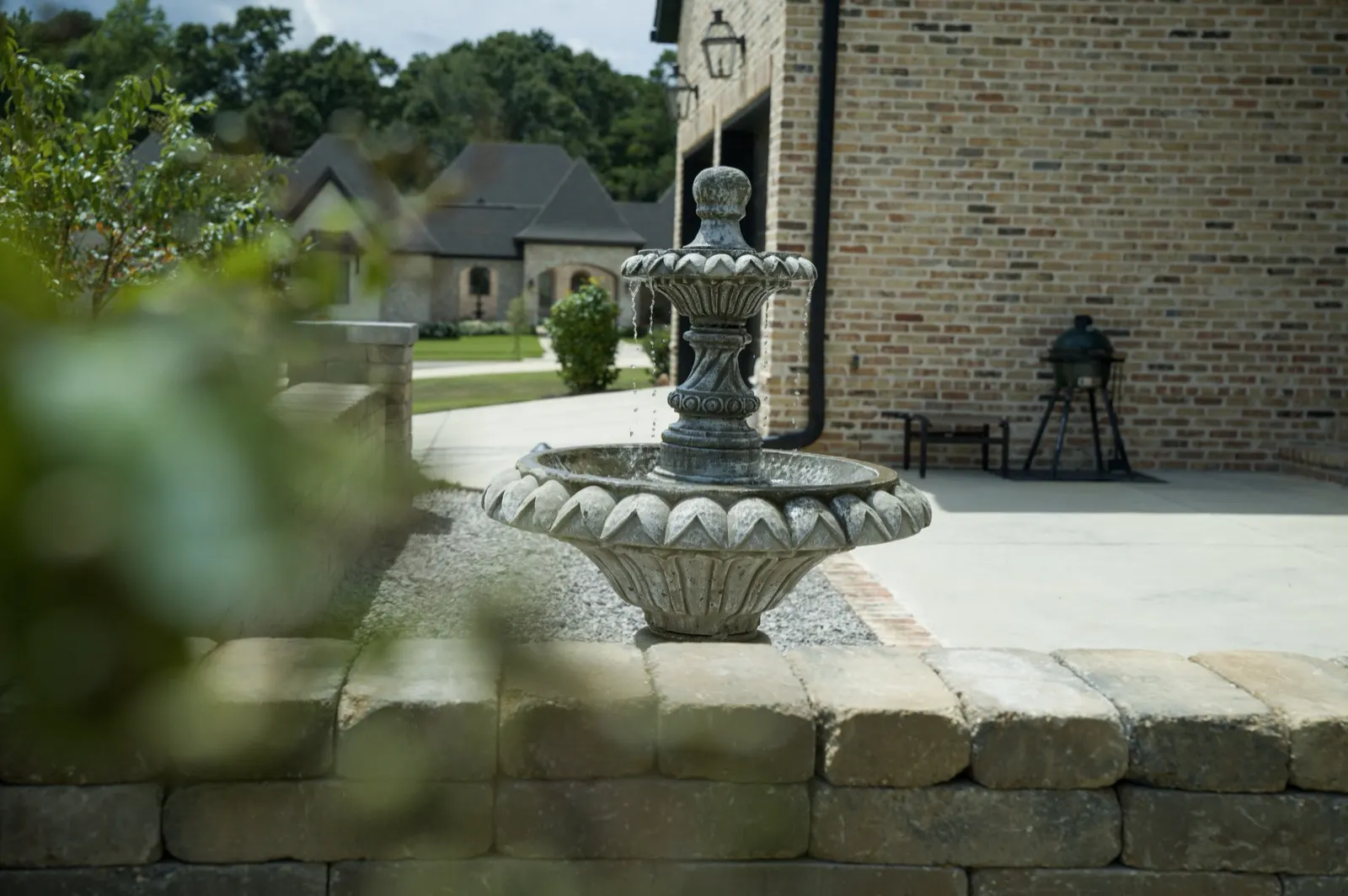 Tiered fountain on white gravel against the brick wall of a home in Fairhope, Alabama