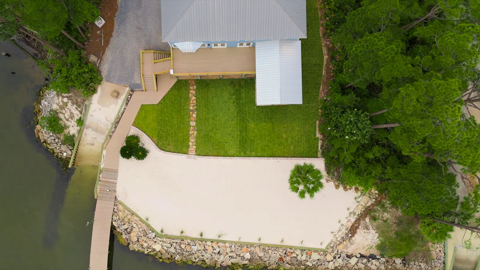 Overhead view of new sod, a stepping-stone path, the sand beach area and rock seawall at a Gulf Shores, Alabama home