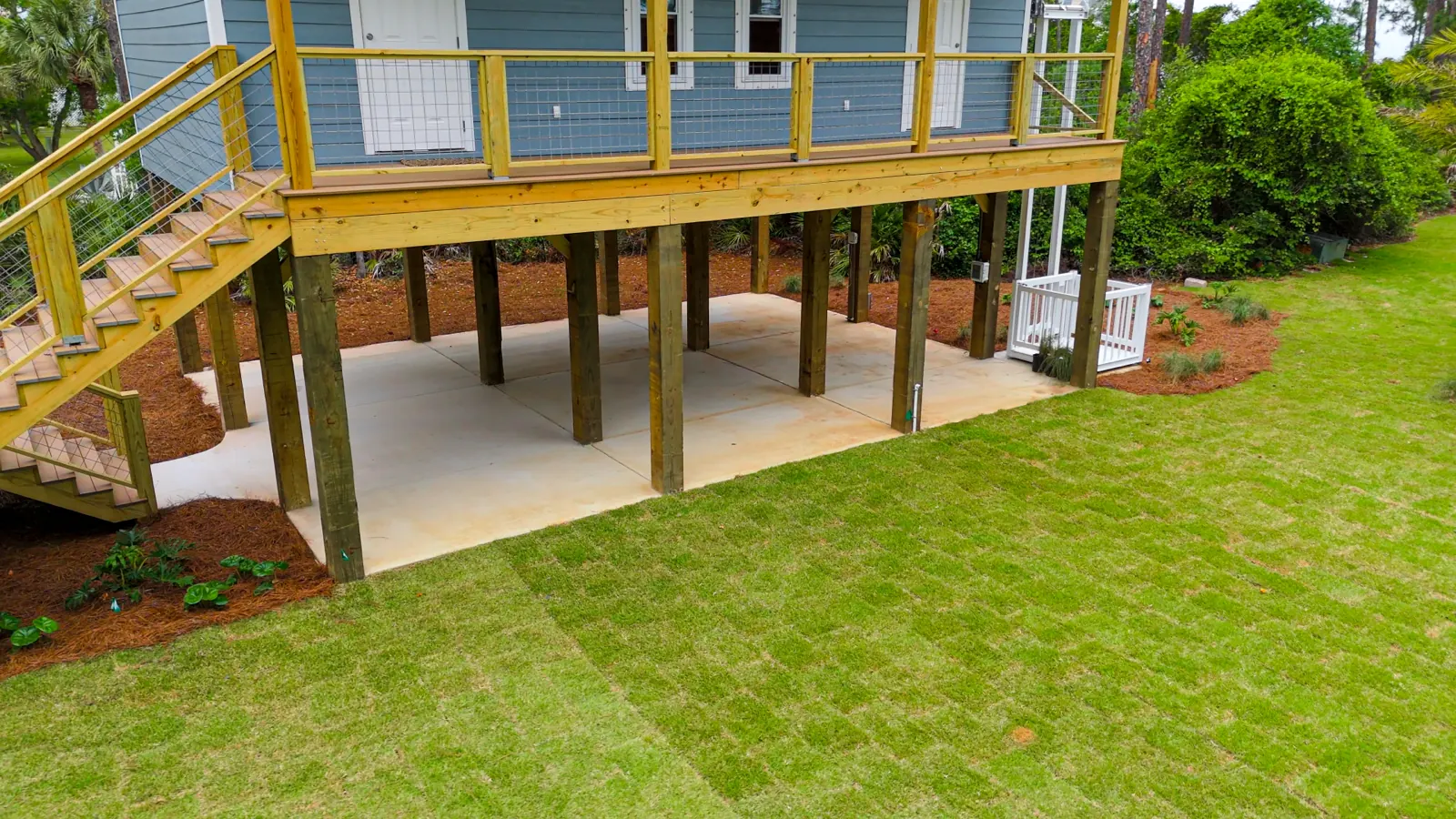 The same Gulf Shores, Alabama yard after new sod, mulch beds and a concrete pad were installed under the deck