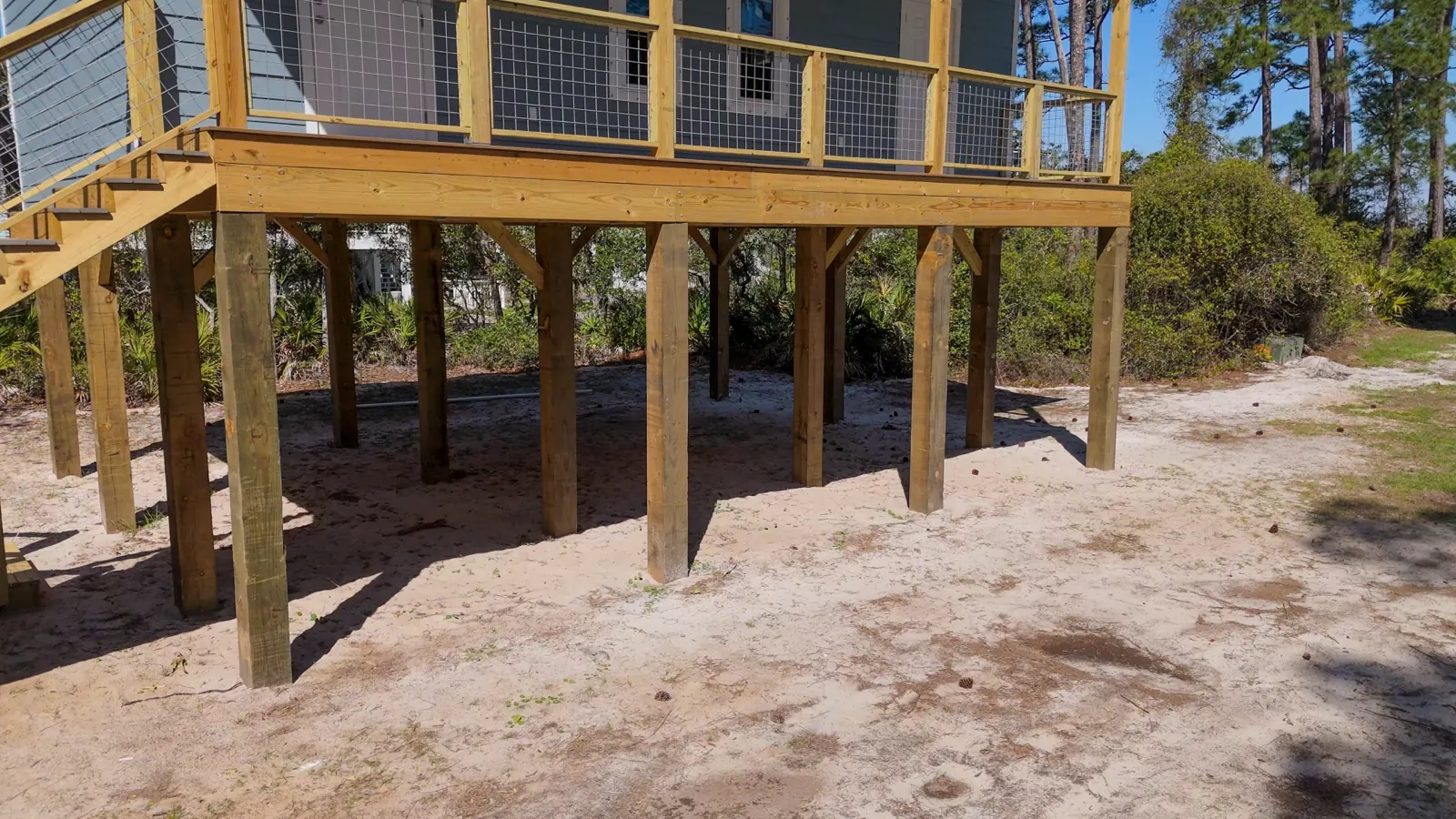 Bare sand under an elevated deck before landscaping at a Gulf Shores, Alabama home