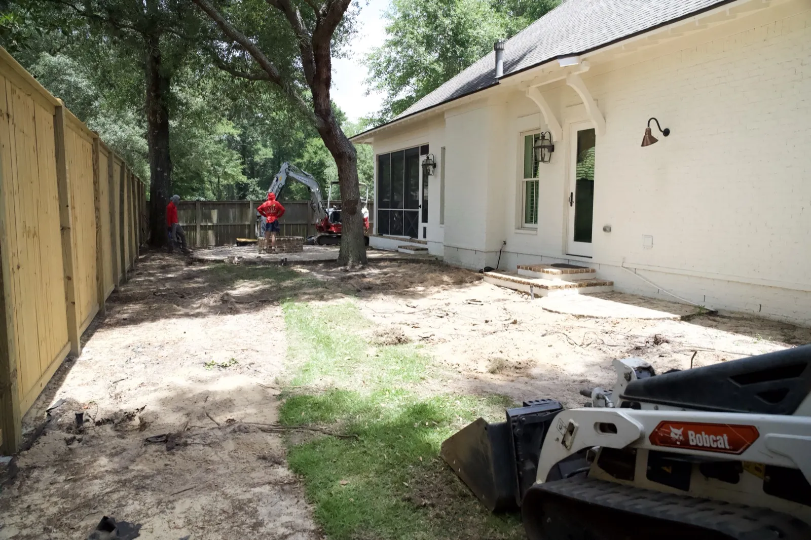 Skid steer and crew mid-demolition in a Point Clear, Alabama backyard renovation