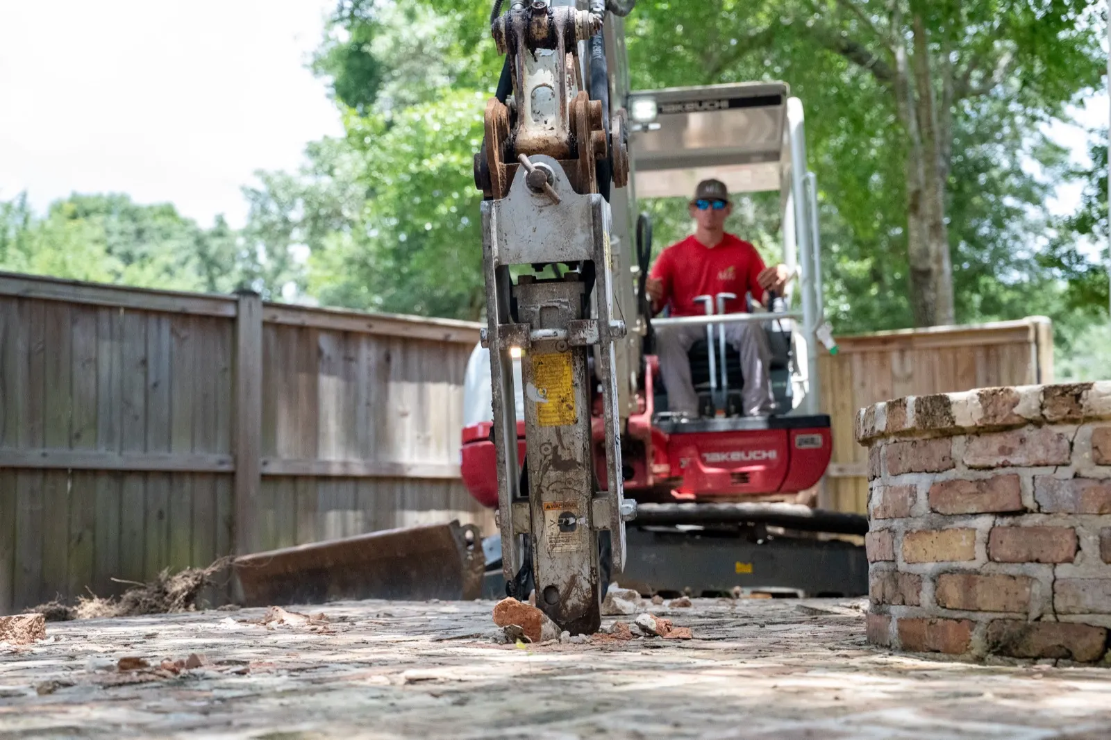 Mini excavator running a hydraulic breaker through an old brick patio in Point Clear, Alabama
