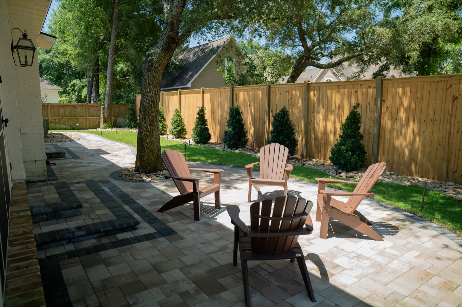 Wide view of a finished paver patio with Adirondack chairs in a Point Clear, Alabama backyard