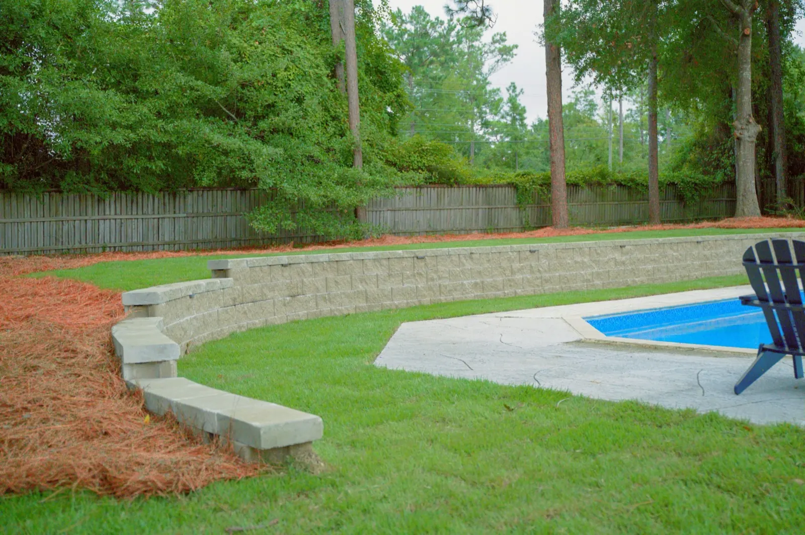 New sod laid next to a concrete pool deck and retaining wall at a Baldwin County, Alabama backyard